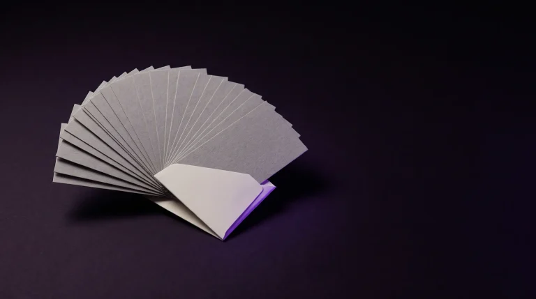 Harmaat paperilaput viuhkana, jotka kokoontuvat yhteen violettireunaiseen korttiin