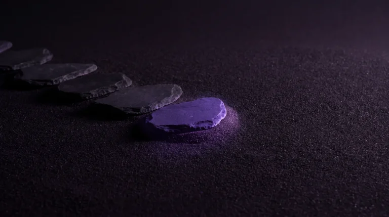 Viisi astinkiveä tummalla hiekalla, viimeinen kivi violetti